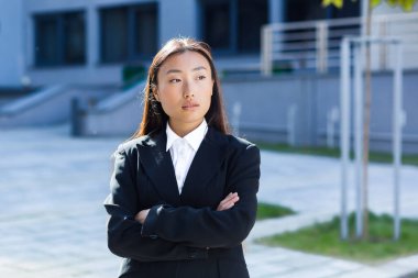 İş kıyafetleri giymiş düşünceli bir Asyalı iş kadınının portresi.