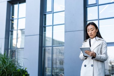 Tablet bilgisayar kullanan bir iş kadını, ofis yakınındaki bir ofis çalışanı, düşünceli ve başarılı bir kadın serbest çalışan.