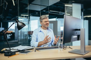 Kıdemli ve deneyimli iş adamı, monitöre kızgın görünüyor, kötü performanstan şikayetçi, işteki adamdan.