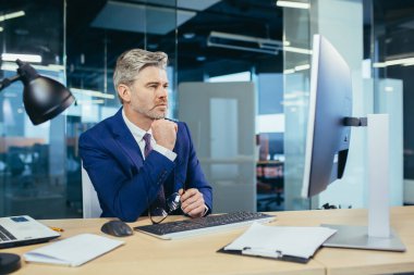 Modern ofiste bilgisayar başında çalışan dalgın bir patron, başarılı bir iş adamı.