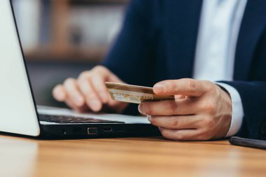 Asyalı işadamının online alışveriş yaparken çekilmiş yakın plan fotoğrafı, dizüstü bilgisayar kullanan adam, kredi kartı tutan adam.