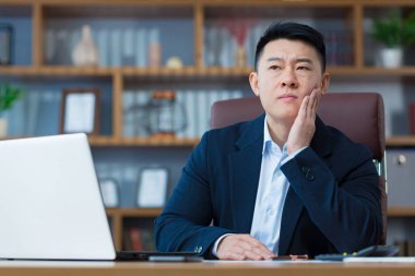 Ofiste çalışan bir iş adamı, masada oturan Asyalı yorgun ve şiddetli bir diş ağrısı var.