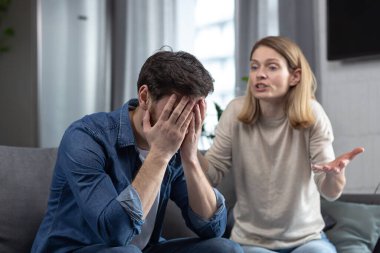 Aile kavgası, kadın kavga eder ve kaybedenin kocasına bağırır, evde oturan çift kanepede oturur.