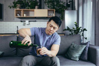 Asyalı bir adam evde yalnız, depresyonda, güçlü alkol içiyor, bekar bir adam.