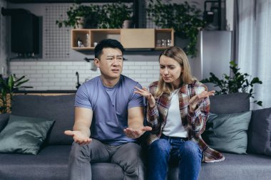 Aile kavgası, kadın kocasından şikayetçi. İnternetten bir psikologla görüşüyor. Evdeki koltukta oturan çok kültürlü bir çift.