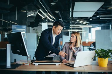 Ofiste oturan bilgisayar monitörüne bakan bir projede danışmanlık yapan iki iş adamı. Asyalı erkek çalışan iş arkadaşı, meslektaşlarının fikir ve stratejilerini, muhasebecisini ve mali raporunu açıklıyor