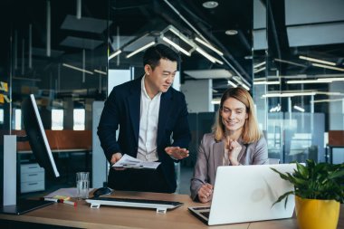 Ofiste oturan bilgisayar monitörüne bakan bir projede danışmanlık yapan iki iş adamı. Asyalı erkek çalışan iş arkadaşı, meslektaşlarının fikir ve stratejilerini, muhasebecisini ve mali raporunu açıklıyor