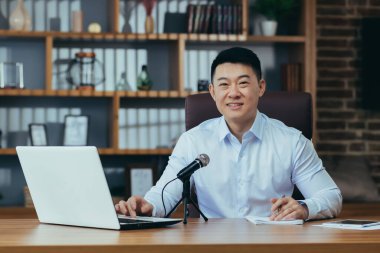 Asyalı serbest yazar ses yayınlarını kaydeder, işadamı ofiste çalışır, profesyonel mikrofon ve dizüstü bilgisayar kullanır