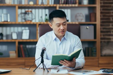 Asyalı serbest yazar ses yayınlarını kaydeder, işadamı ofiste çalışır, profesyonel mikrofon ve dizüstü bilgisayar kullanır