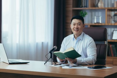 Asyalı serbest yazar ses yayınlarını kaydeder, işadamı ofiste çalışır, profesyonel mikrofon ve dizüstü bilgisayar kullanır