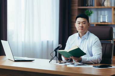 Asyalı serbest yazar ses yayınlarını kaydeder, işadamı ofiste çalışır, profesyonel mikrofon ve dizüstü bilgisayar kullanır