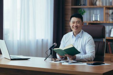 Asyalı serbest yazar ses yayınlarını kaydeder, işadamı ofiste çalışır, profesyonel mikrofon ve dizüstü bilgisayar kullanır