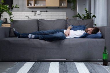 Mutfaktaki kanepede uyuyan sarhoş adam.