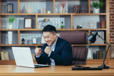 Mutlu iş adamı başarılı bir sözleşmenin sonucunu kutluyor, dizüstü bilgisayara bakıyor ve seviniyor