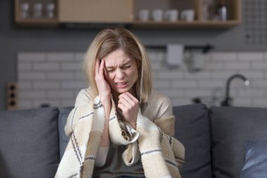 Kadının kendisi evde battaniyenin altında oturuyor, şiddetli bir baş ağrısı var.