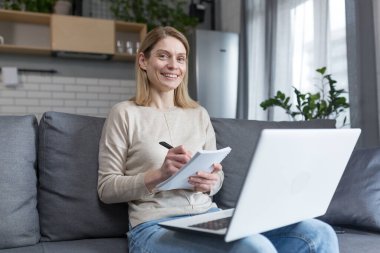 Evdeki kadın portresi, öğrenci kayıt dersi, online eğitim için dizüstü bilgisayar kullanımı, kanepede oturmak.