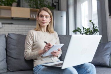 Evdeki kadın portresi, öğrenci kayıt dersi, online eğitim için dizüstü bilgisayar kullanımı, kanepede oturmak.