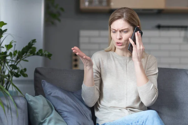 Genervte Frau Sitzt Hause Auf Der Couch Und Telefoniert — Stockfoto