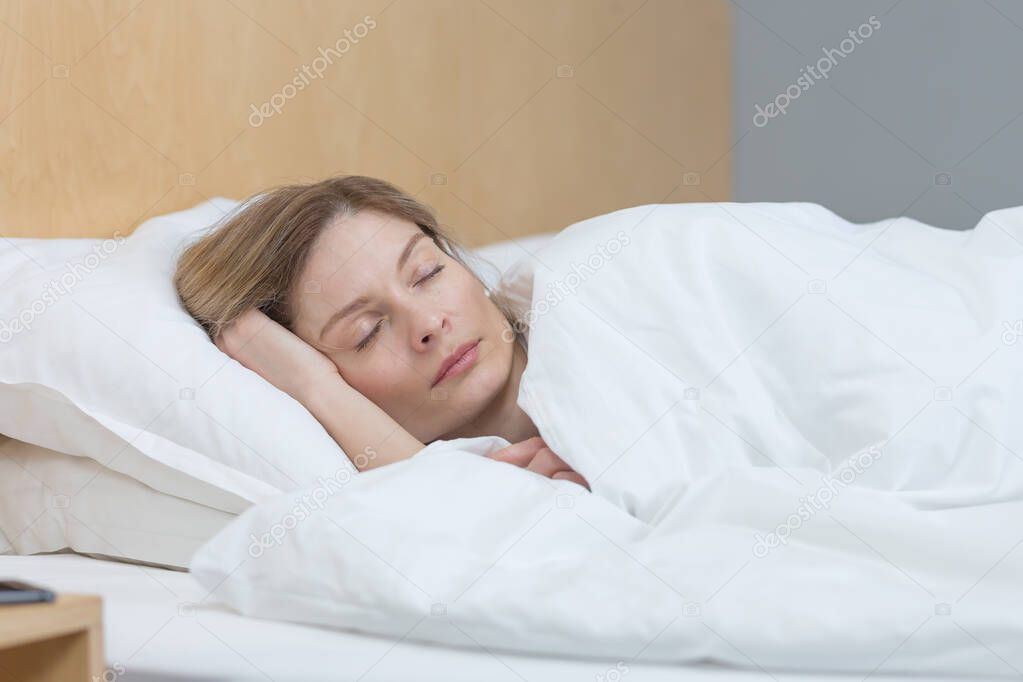Woman sleeping at home under a blanket with eyes closed resting
