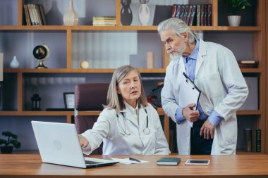 Kıdemli doktorlar kliniğin klasik ofisinde danışmanlık ve pratik yaparlar, hastaların teşhislerini tartışırlar.