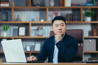Bilgisayarda çalışan bir adam, klasik ofiste Asyalı, proje üzerinde çalışan bir patron.