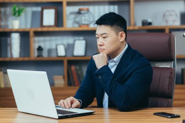 Bilgisayarda çalışan bir adam, klasik ofiste Asyalı, proje üzerinde çalışan bir patron.