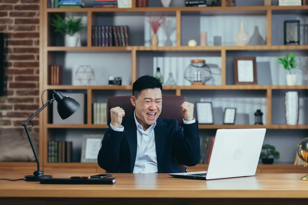 Mutlu iş adamı başarılı bir sözleşmenin sonucunu kutluyor, dizüstü bilgisayara bakıyor ve seviniyor