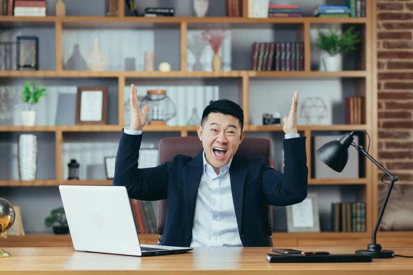 Mutlu iş adamı başarılı bir sözleşmenin sonucunu kutluyor, dizüstü bilgisayara bakıyor ve seviniyor