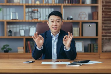 Mutlu iş adamı, iş arkadaşlarıyla görüntülü konuşma kamerasına bakıyor.