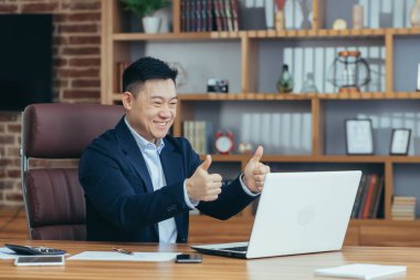 Yakışıklı Asyalı genç bir adam, iş adamı, avukat, yönetmen ofisteki bir bilgisayardan video görüşmesi yapıyor, toplantı yapıyor, danışmanlık yapıyor, tartışıyorlar.