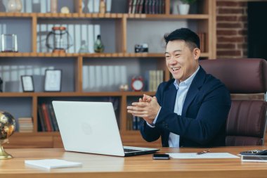 Yakışıklı Asyalı genç bir adam, iş adamı, avukat, yönetmen ofisteki bir bilgisayardan video görüşmesi yapıyor, toplantı yapıyor, danışmanlık yapıyor, tartışıyorlar.