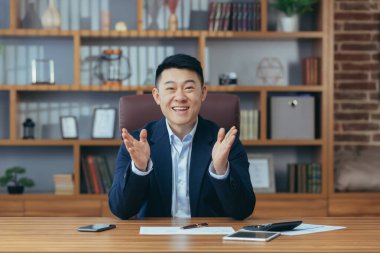 Genç yakışıklı bir Asyalı diplomat, yönetmen, kameraya gülümseyen iş adamı portresi, bir sözleşme imzalıyor, toplantı yapıyor, video konferansı düzenliyor, danışmanlık yapıyor. Açıklar, ofisteki bir masada oturur.