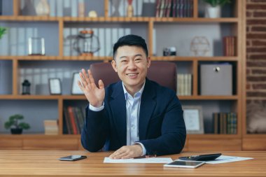 Genç yakışıklı bir Asyalı diplomat, yönetmen, kameraya gülümseyen iş adamı portresi, bir sözleşme imzalıyor, toplantı yapıyor, video konferansı düzenliyor, danışmanlık yapıyor. Açıklar, ofisteki bir masada oturur.