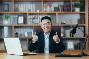 Genç yakışıklı bir Asyalı diplomat, yönetmen, kameraya gülümseyen iş adamı portresi, bir sözleşme imzalıyor, toplantı yapıyor, video konferansı düzenliyor, danışmanlık yapıyor. Açıklar, ofisteki bir masada oturur.