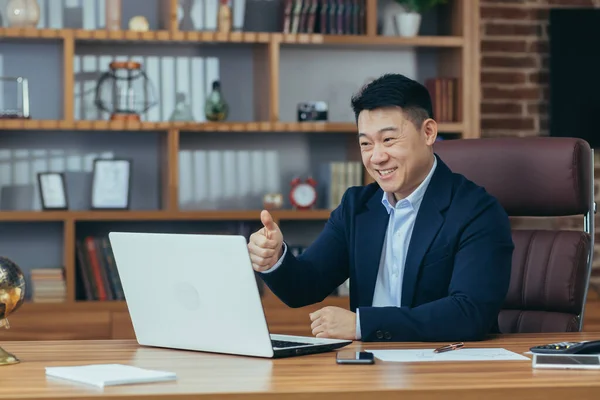 stock image Young handsome asian man, businessman, lawyer, director talking on a video call from a laptop in the office, holds a meeting, consultation, discussion