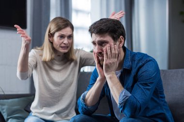 Aile kavgası, kadın kavga eder ve kaybedenin kocasına bağırır, evde oturan çift kanepede oturur.