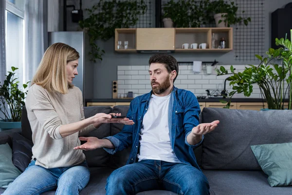 Bir kadın kocasıyla tartışıyor, az para kazanan tembel bir adamın iddiası, evli bir çift kanepede oturuyor.