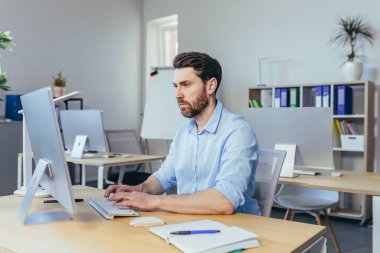 Düşünen bir iş adamı, gün içinde modern bir ofiste çalışmak, bir masada oturmak, bilgisayarla çalışmak, bir iş sözleşmesini çözmeyi düşünmek.
