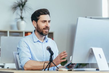 Başarılı ve mutlu iş koçu akıl hocası, ses podcast 'ini kaydediyor, profesyonel mikrofon kullanıyor, modern beyaz ofiste iş adamı, çevrimiçi iş eğitimi yürütüyor.