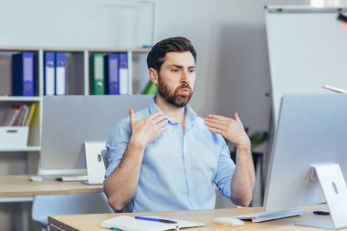 Ofiste ateşli, gömlekli bir işadamı, parlak, modern bir ofiste çalışıyor, kollarını sallıyor ve kendine çeki düzen vermeye çalışıyor.