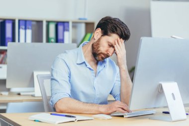 Düşünceli ve üzgün bir adam modern bir ofiste çalışıyor, iş adamı depresif bir şekilde evde elini tutuyor.