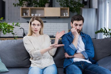 Family conflict. Young couple, family, man and woman on a reception at the psychologist. Sit on the couch, talk, gesture. discuss, argue.