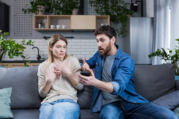 Family conflict at home. An angry man suspects a woman of treason, shouts at her, demands explanations, shows the phone, messages.