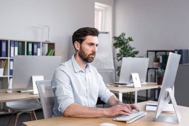 Bilgisayarın ofisinde çalışan konsantre ve düşünceli bir işadamı, evrak komisyoncusu, monitöre bakan bir adam.