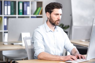 Bilgisayarın ofisinde çalışan konsantre ve düşünceli bir işadamı, evrak komisyoncusu, monitöre bakan bir adam.