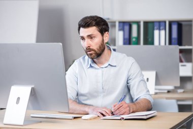 Concentrated and pensive businessman working in the office at the computer, paperwork broker, man looking at the monitor