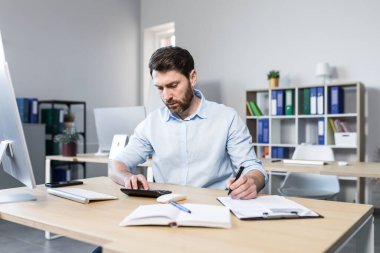 Ofiste belgelerle çalışan bir iş adamı, mali raporları inceleyen bir adam.