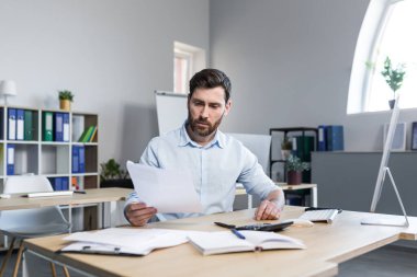 Ofiste belgelerle çalışan bir iş adamı, mali raporları inceleyen bir adam.