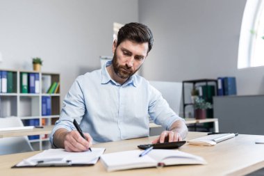 Ofiste belgelerle çalışan bir iş adamı, mali raporları inceleyen bir adam.