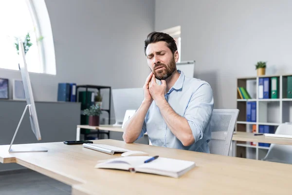 Man at work, has a severe toothache, businessman works in the office with a computer